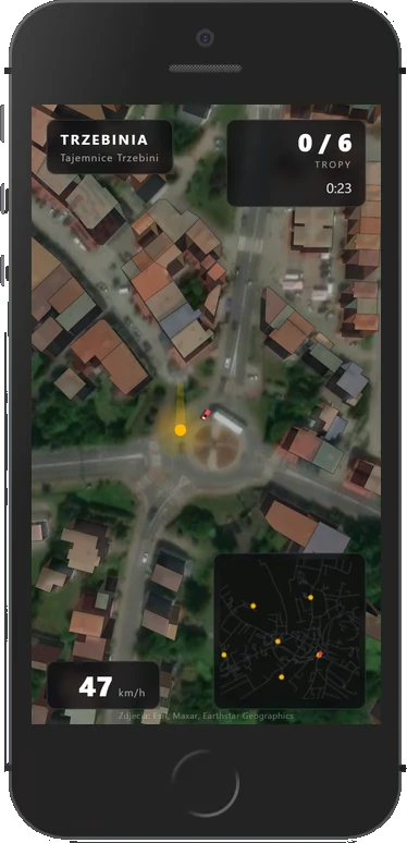 Przejazd po Trzebini na ekranie telefonu: widok z góry na rondo w środku miasta, licznik tropów 0/6, czas 0:23 i prędkość 47 km/h